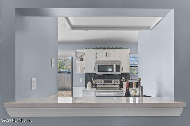 kitchen with tasteful backsplash, stainless steel appliances, a textured ceiling, and white cabinets