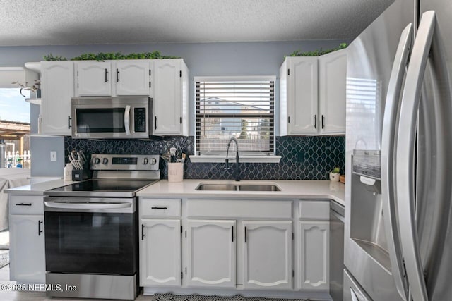 kitchen with sink, white cabinetry, backsplash, stainless steel appliances, and a textured ceiling