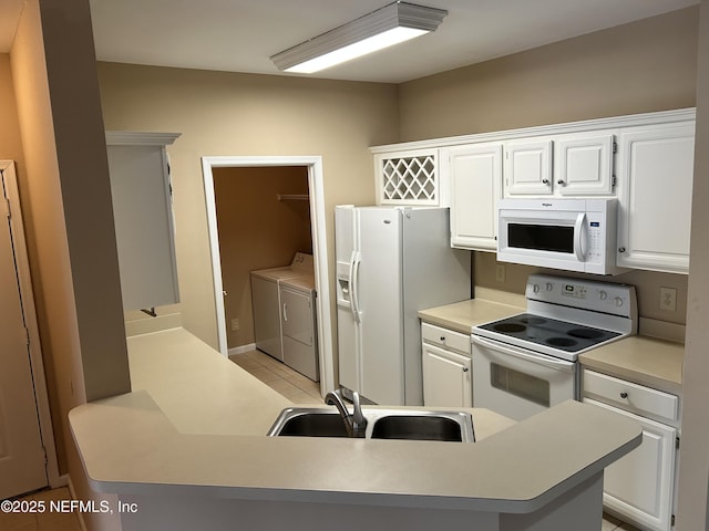 kitchen with washer and dryer, white appliances, and white cabinets