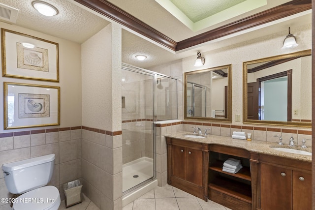 bathroom featuring vanity, a shower with door, crown molding, tile walls, and tile patterned flooring