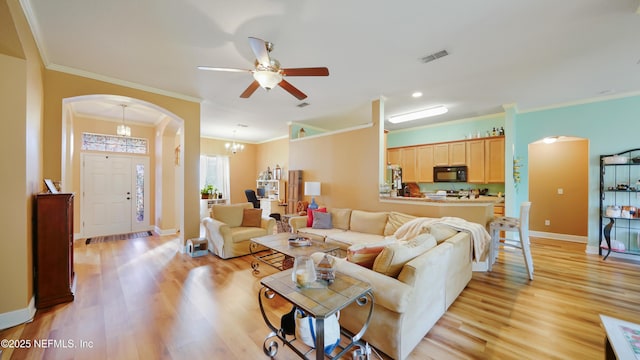 living room featuring light wood-type flooring, ceiling fan with notable chandelier, and crown molding