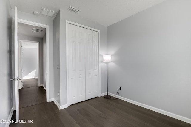 unfurnished bedroom featuring dark hardwood / wood-style floors and a closet