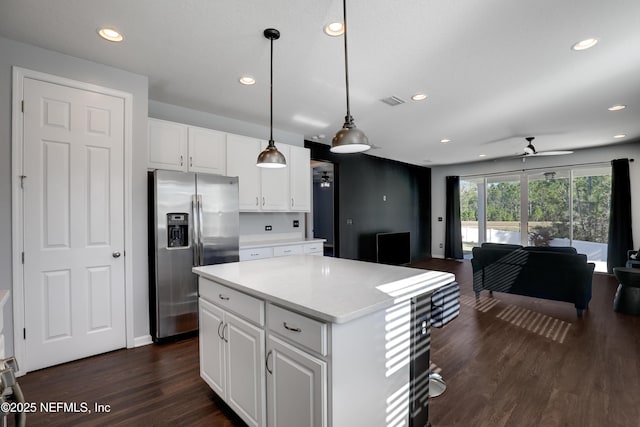 kitchen featuring pendant lighting, stainless steel fridge with ice dispenser, ceiling fan, a kitchen island, and white cabinetry