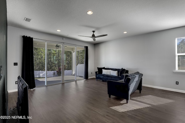 living room featuring ceiling fan, dark hardwood / wood-style flooring, and a textured ceiling