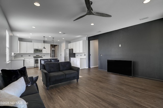 living room with ceiling fan, dark wood-type flooring, and sink