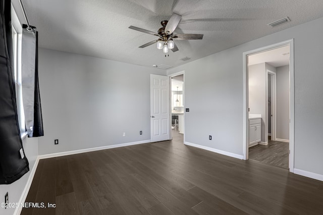 unfurnished bedroom with a textured ceiling, ceiling fan, dark hardwood / wood-style flooring, and ensuite bathroom