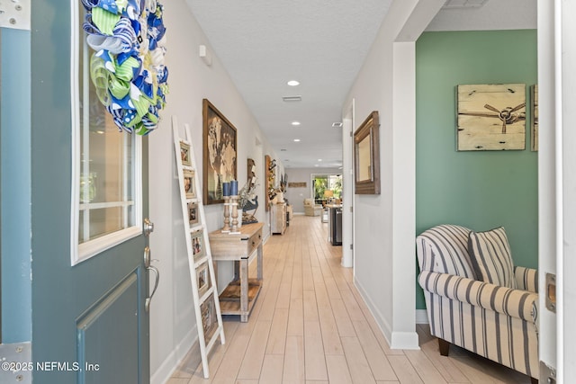 corridor featuring a textured ceiling and light hardwood / wood-style floors