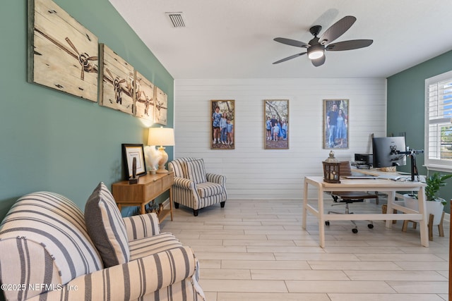 office area with light hardwood / wood-style flooring, ceiling fan, and wooden walls