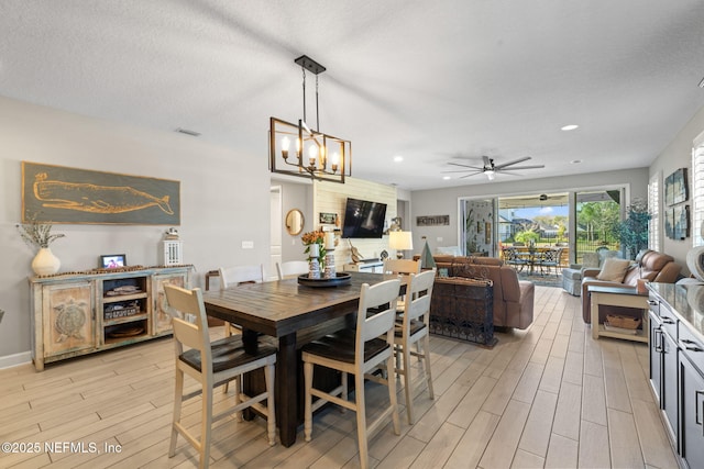 dining space with ceiling fan with notable chandelier and a textured ceiling