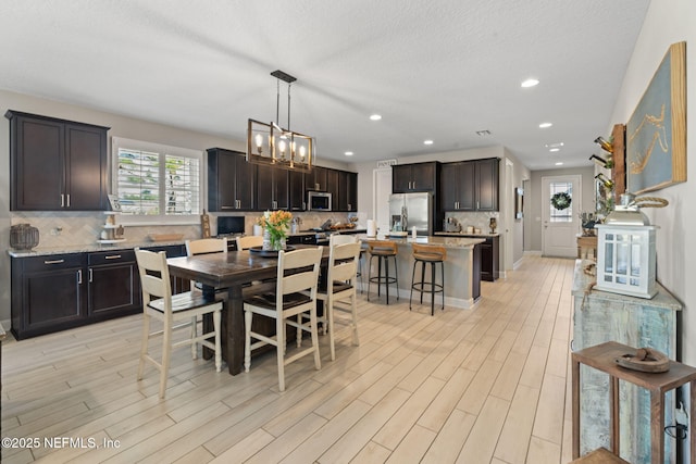 dining space featuring a textured ceiling, light hardwood / wood-style flooring, and a chandelier