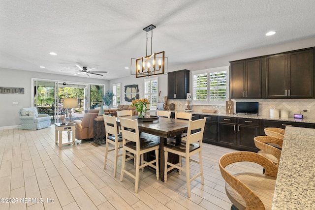 dining room featuring a textured ceiling, ceiling fan with notable chandelier, and a wealth of natural light