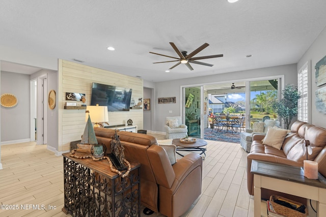 living room featuring ceiling fan, light hardwood / wood-style floors, and a textured ceiling