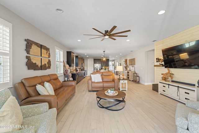 living room with light hardwood / wood-style floors and ceiling fan with notable chandelier