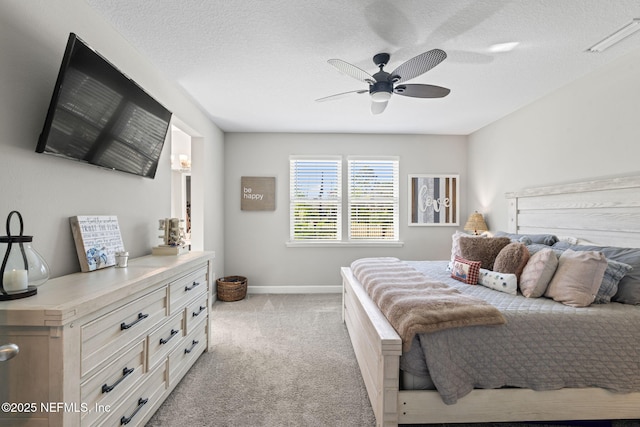 bedroom featuring light carpet, a textured ceiling, and ceiling fan