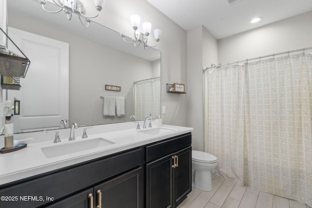 bathroom with toilet, vanity, and an inviting chandelier