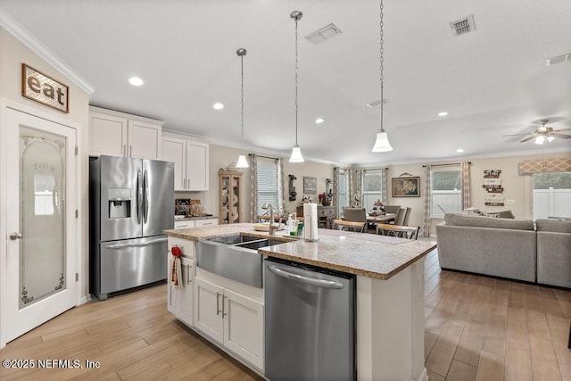 kitchen with white cabinetry, crown molding, an island with sink, and stainless steel appliances