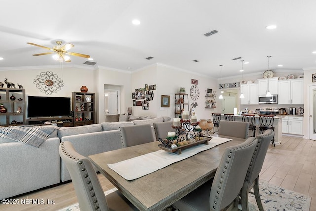 dining space with ceiling fan and ornamental molding