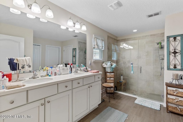 bathroom with vanity, a textured ceiling, and an enclosed shower