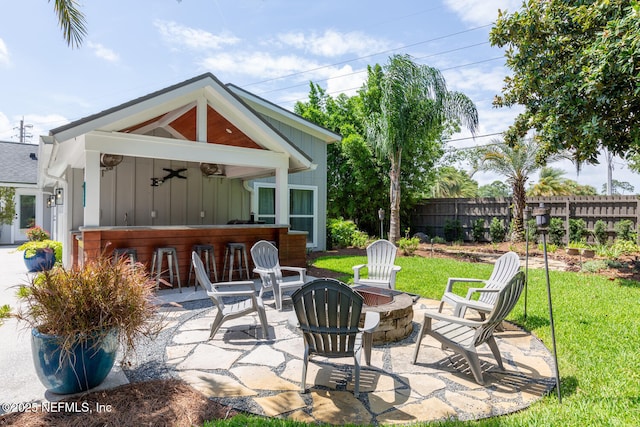 view of patio / terrace featuring exterior bar, ceiling fan, and an outdoor fire pit