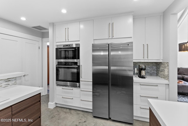 kitchen featuring white cabinetry, stainless steel appliances, and backsplash