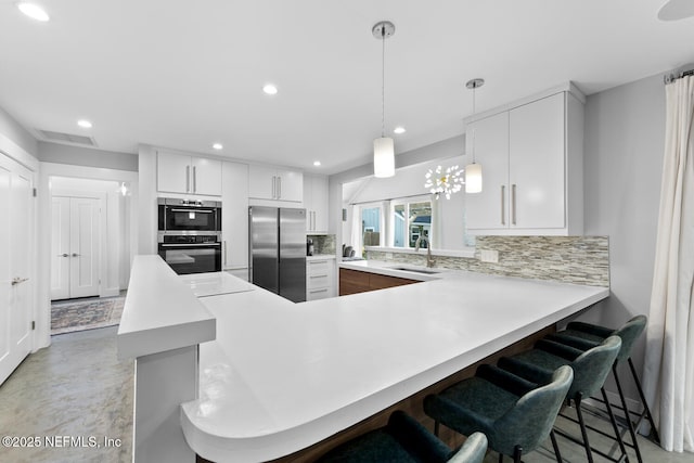 kitchen with decorative light fixtures, white cabinetry, stainless steel fridge, decorative backsplash, and kitchen peninsula