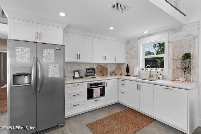 kitchen with white cabinetry, sink, backsplash, and stainless steel appliances