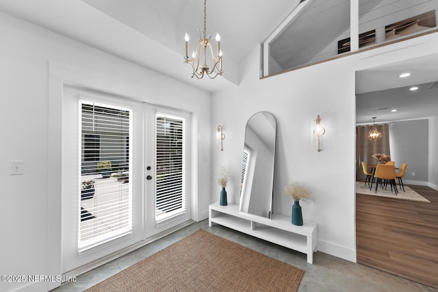 foyer entrance featuring an inviting chandelier, concrete flooring, french doors, and lofted ceiling