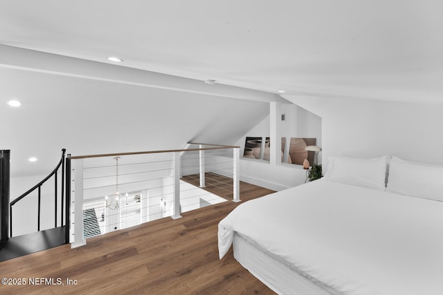 bedroom with vaulted ceiling, hardwood / wood-style floors, and a notable chandelier