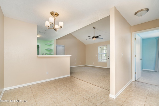 tiled empty room featuring ceiling fan with notable chandelier and lofted ceiling