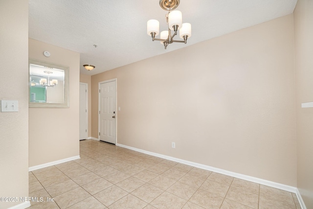 tiled empty room with a textured ceiling and an inviting chandelier