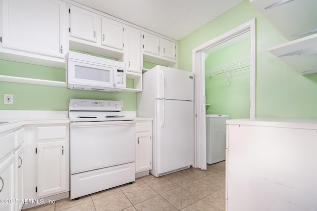 kitchen with light tile patterned floors, white cabinets, white appliances, and washer / dryer