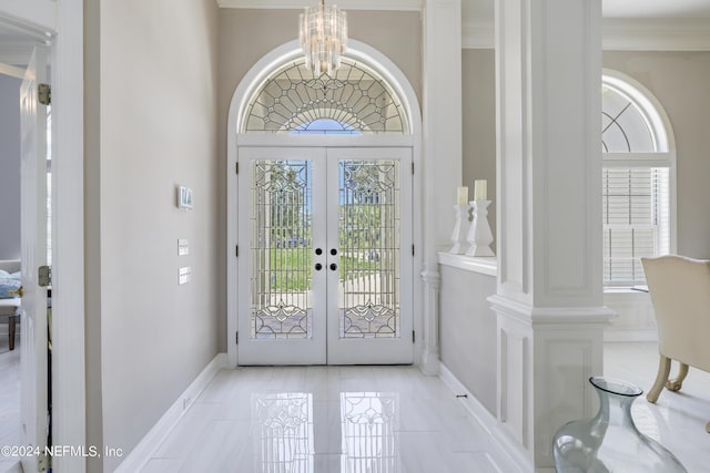 entryway with a chandelier, decorative columns, and french doors