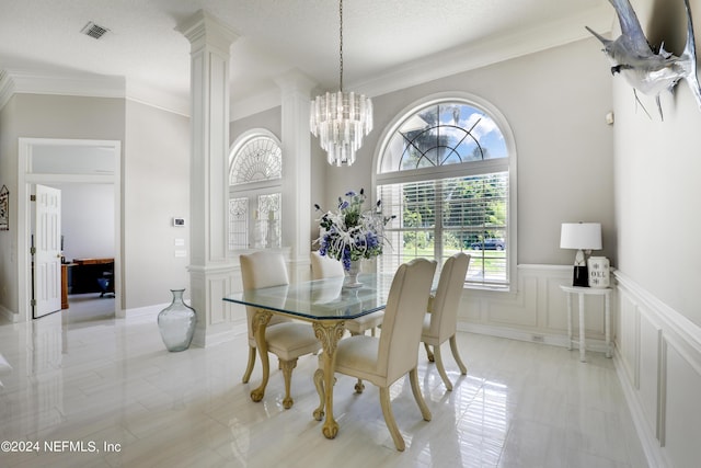 dining area with ornamental molding, ornate columns, a textured ceiling, and an inviting chandelier