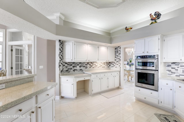 kitchen with a textured ceiling, stainless steel double oven, and white cabinetry