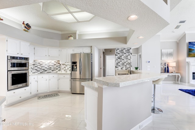 kitchen featuring a kitchen bar, white cabinetry, stainless steel appliances, and tasteful backsplash