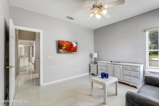 sitting room with a textured ceiling and ceiling fan