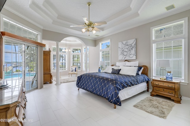 bedroom with ceiling fan, a raised ceiling, ornamental molding, and decorative columns