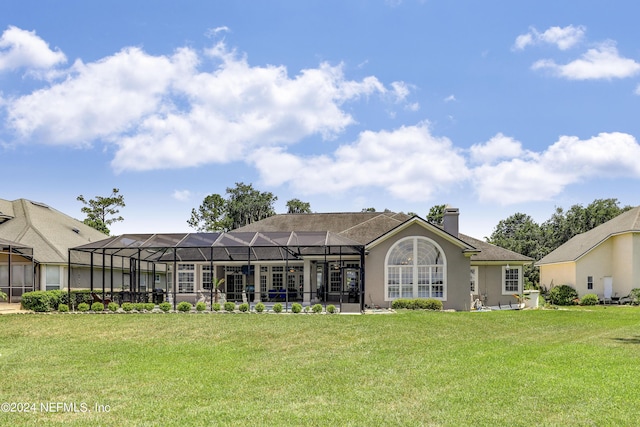 back of property with glass enclosure and a yard