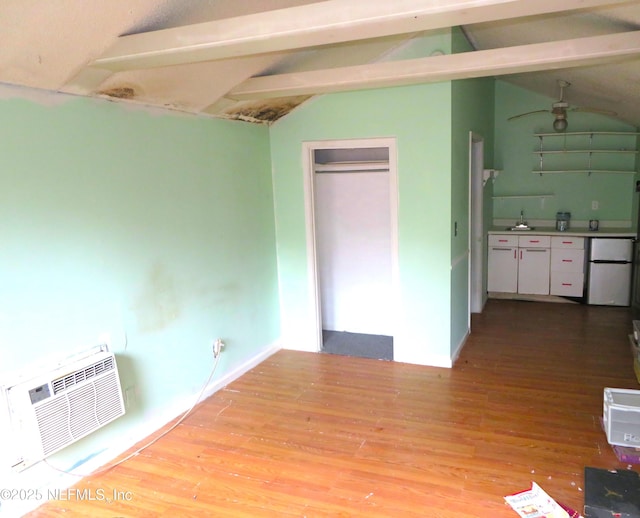 unfurnished bedroom featuring vaulted ceiling with beams, light hardwood / wood-style flooring, refrigerator, and a wall mounted AC