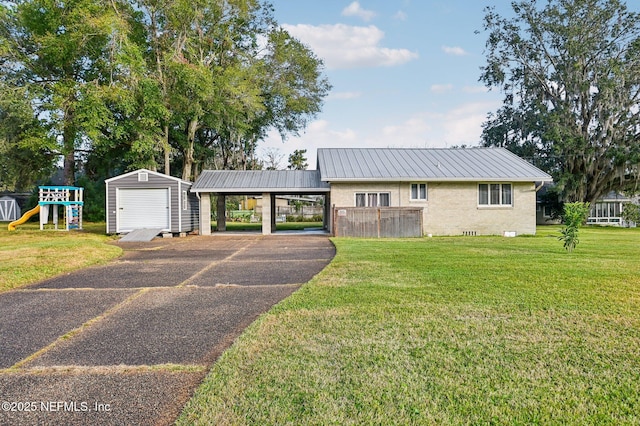 view of front of property featuring a front yard, a playground, a shed, and a carport