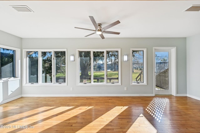 unfurnished sunroom featuring ceiling fan and a healthy amount of sunlight