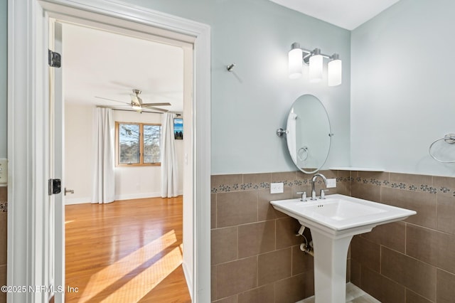 bathroom featuring ceiling fan, tile walls, and hardwood / wood-style flooring