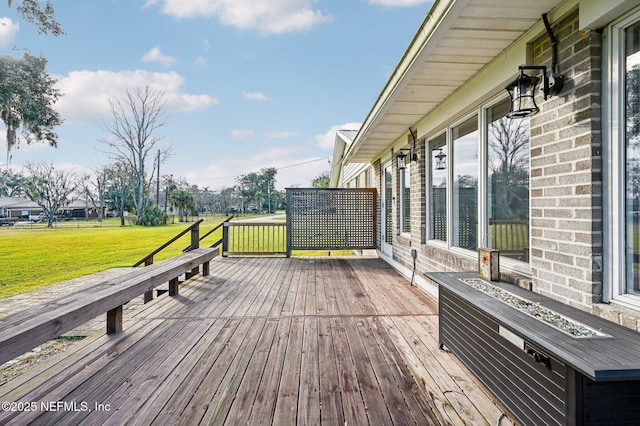 wooden deck featuring an outdoor fire pit and a lawn