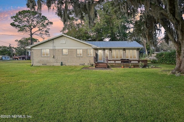 back house at dusk featuring a lawn