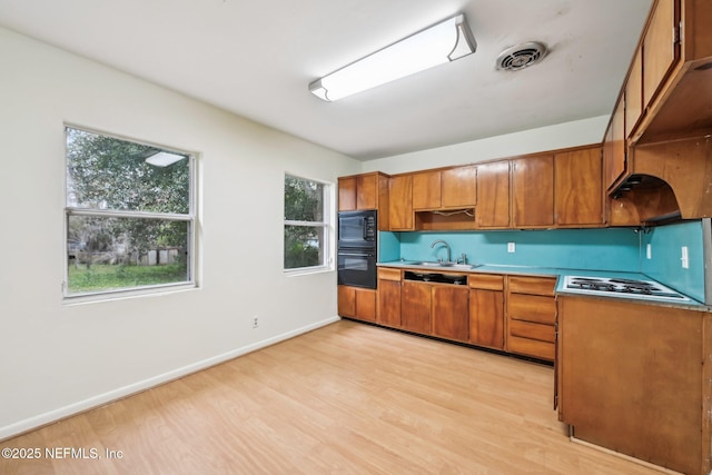 kitchen with black appliances, light wood-type flooring, and sink