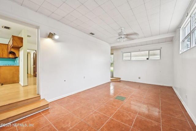 empty room with ceiling fan, plenty of natural light, and tile patterned floors