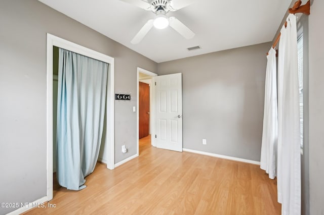 unfurnished bedroom with light wood-type flooring, ceiling fan, and a closet