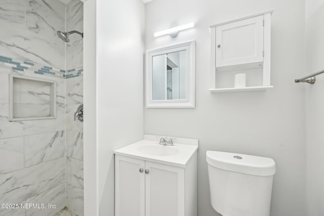 bathroom featuring vanity, toilet, and a tile shower