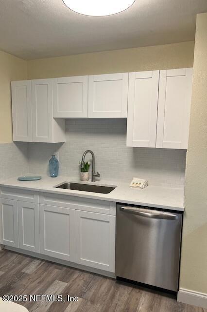 kitchen with white cabinets, stainless steel dishwasher, dark wood-type flooring, and sink