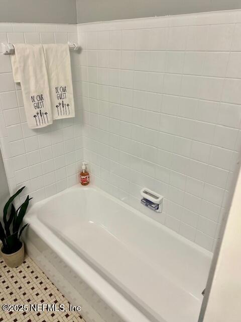 bathroom with tile patterned floors and a washtub